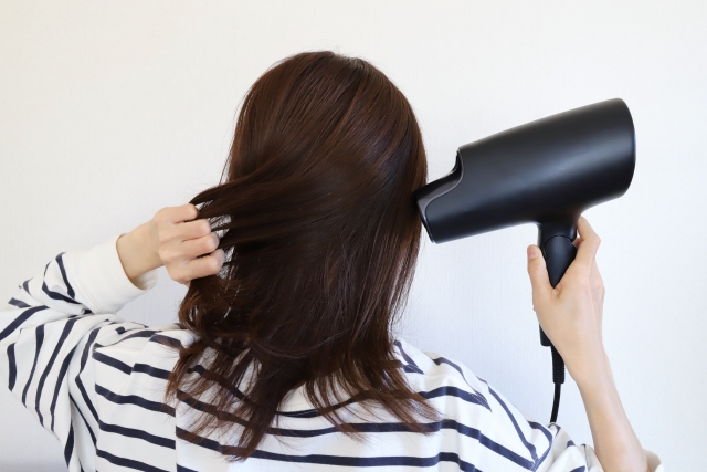 ドライヤーで髪を乾かす女性