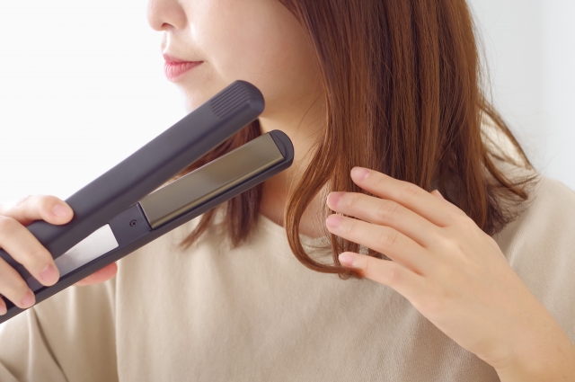 ヘアアイロンを使う女性